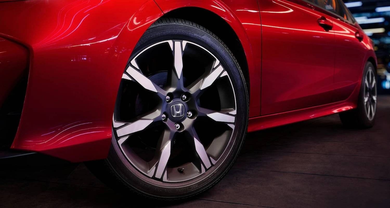 The 2025 Honda Civic Sedan Sport Touring Hybrid in Rallye Red at 3/4 front low angle in outdoor environment