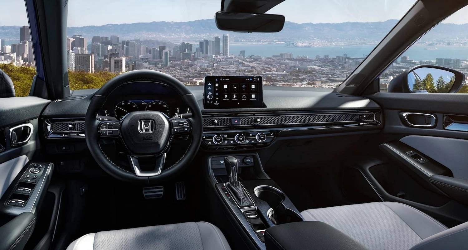 The 2025 Honda Civic Sedan Sport Touring Hybrid in Blue Lagoon Pearl, interior of vehicle at driver POV angle in urban overlook environment