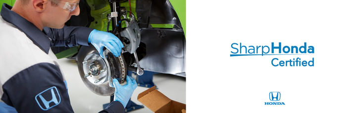 A technician wearing blue gloves works on a car brake system, with a Honda logo and "Sharp Honda Certified" text prominently displayed.