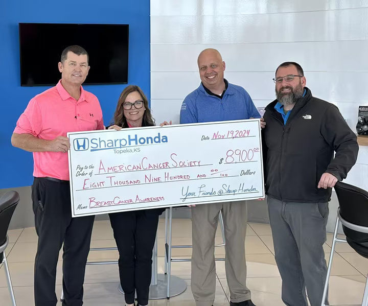Four people holding a large check from Sharp Honda to the American Cancer Society for $8,900.