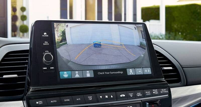 The 2026 Honda Odyssey view from driver POV, close up of rear view camera screen, with home in background out windshield