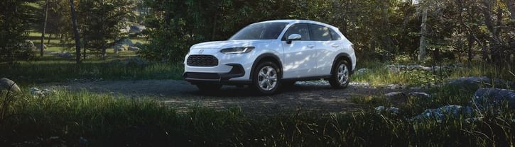 Front driver-side view of the 2026 Honda HR-V LX in Platinum White Pearl shown parked in a forested setting