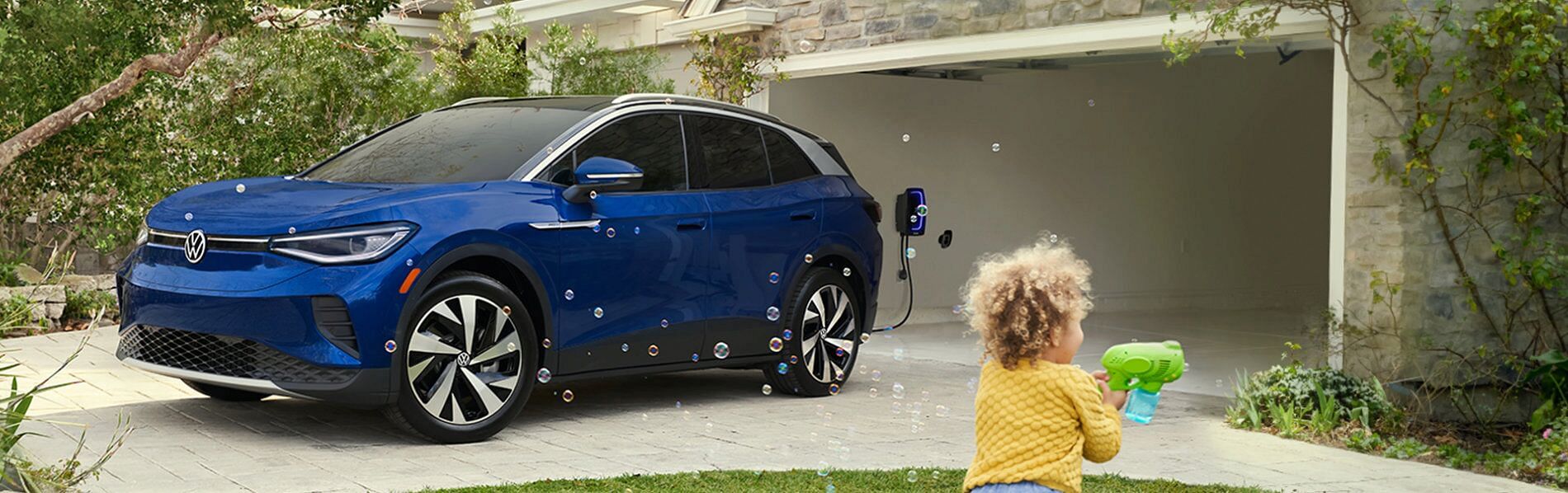 Volkswagen ID.4 2021 parked in the driveway. Child in the foreground playing with soap bubbles