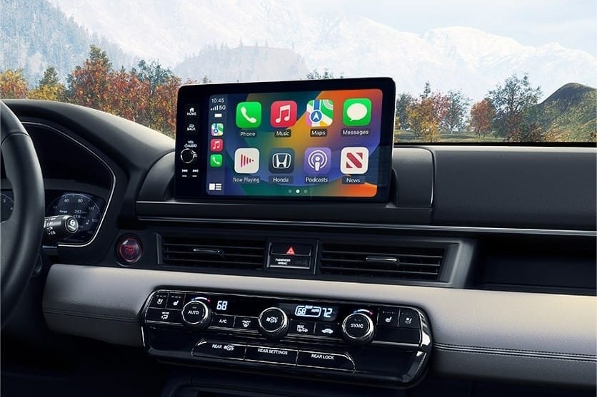 2025 Honda Pilot interior featuring a digital touchscreen display with app icons for music, navigation, and messaging, against a scenic backdrop.