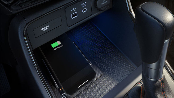 A smartphone lying on a wireless charging pad inside a Honda CR-V.