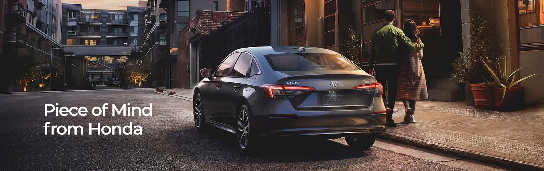 Gray Honda Civic parked in front of a building and couple walking by