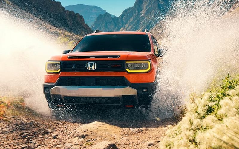 A 2026 Honda Passport drives through a stream of water, showcasing its off-road capabilities in a natural setting.