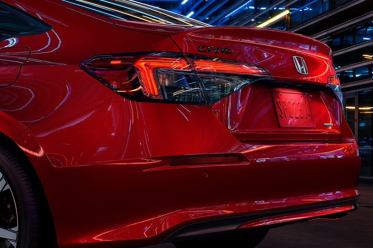 Red 2026 Honda Civic Sedan rear view with illuminated taillights under vibrant neon lights, conveying a sleek and modern urban feel.