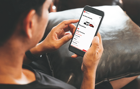 Customer holding phone looking at the Toyota Auto Insurance Self Service Dashboard