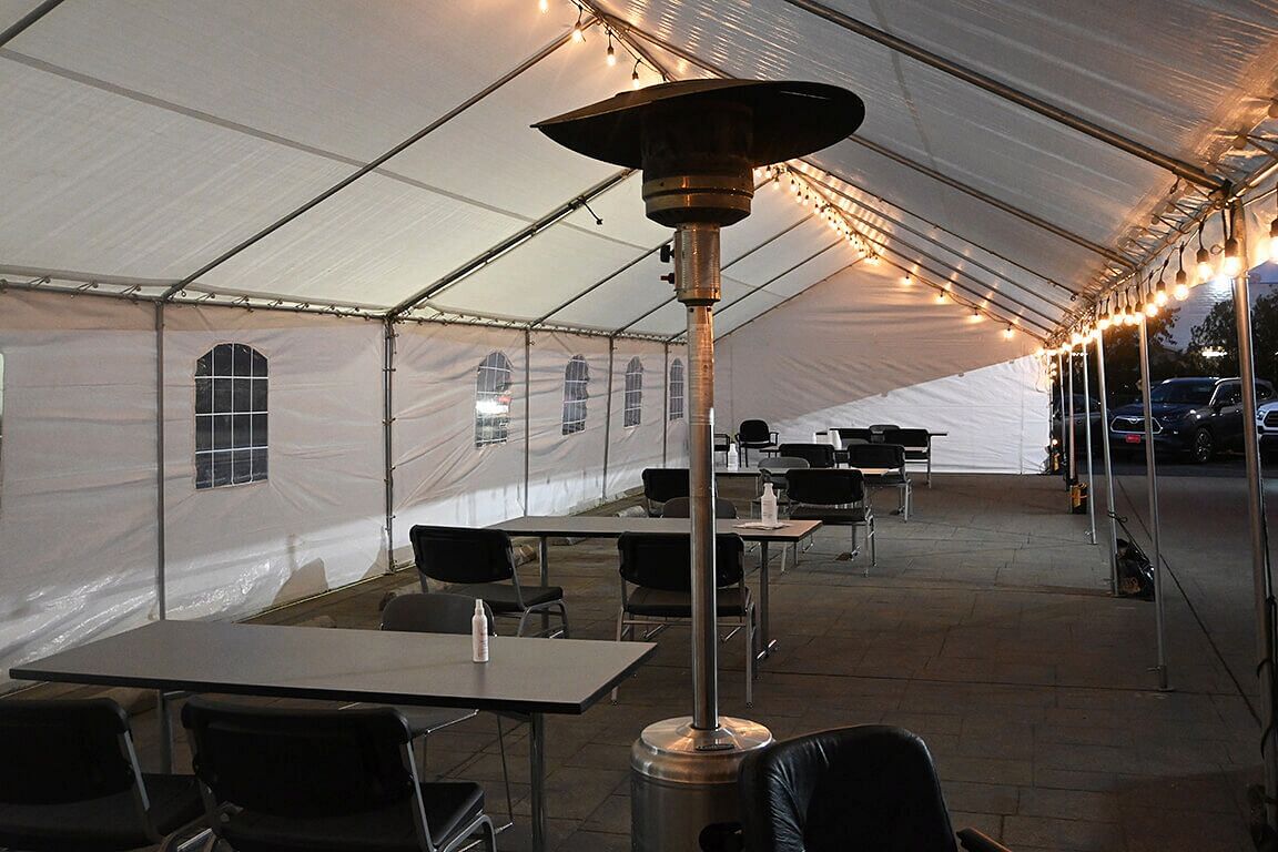 Desks and chairs with warmers under the tent at night