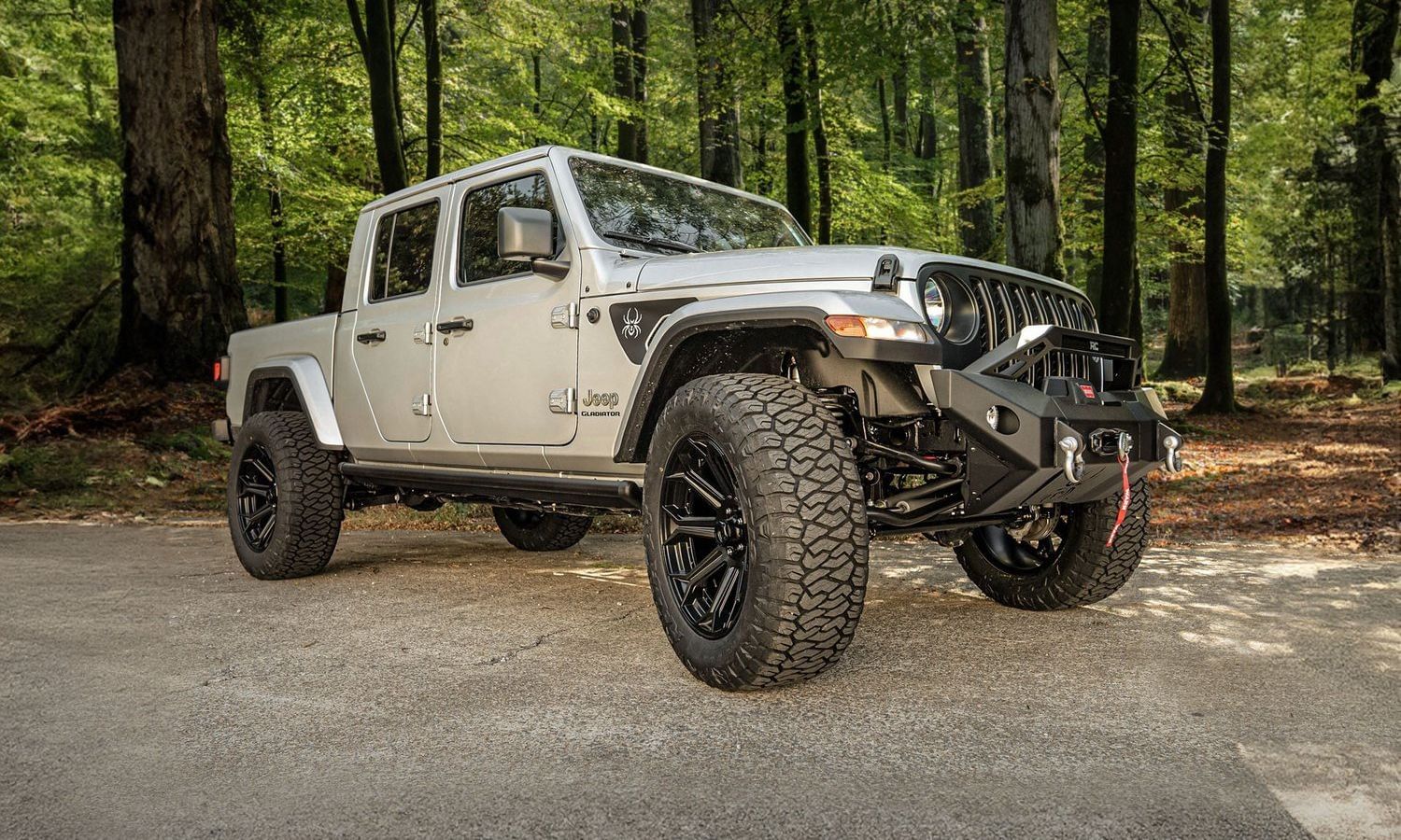 Front view of a Jeep Gladiator Black Widow Edition featuring a prominent large tire, emphasizing its adventurous style.