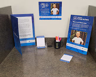 Countertop display for the Subaru Loves to Care initiative featuring informational stands, notepads, and pens.