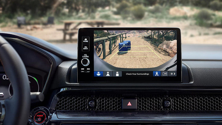 The infotainment screen of a car showing the backup camera view of a campsite.