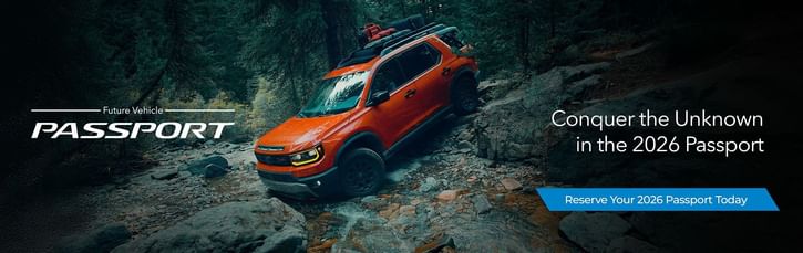An orange 2026 Honda Passport navigates rocky terrain in a wooded landscape, promoting adventure and exploration. Reserve yours today!