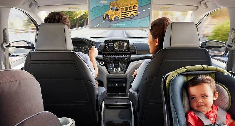 The 2026 Honda Odyssey Elite with man driving and woman in front passenger seat, driving on residential road