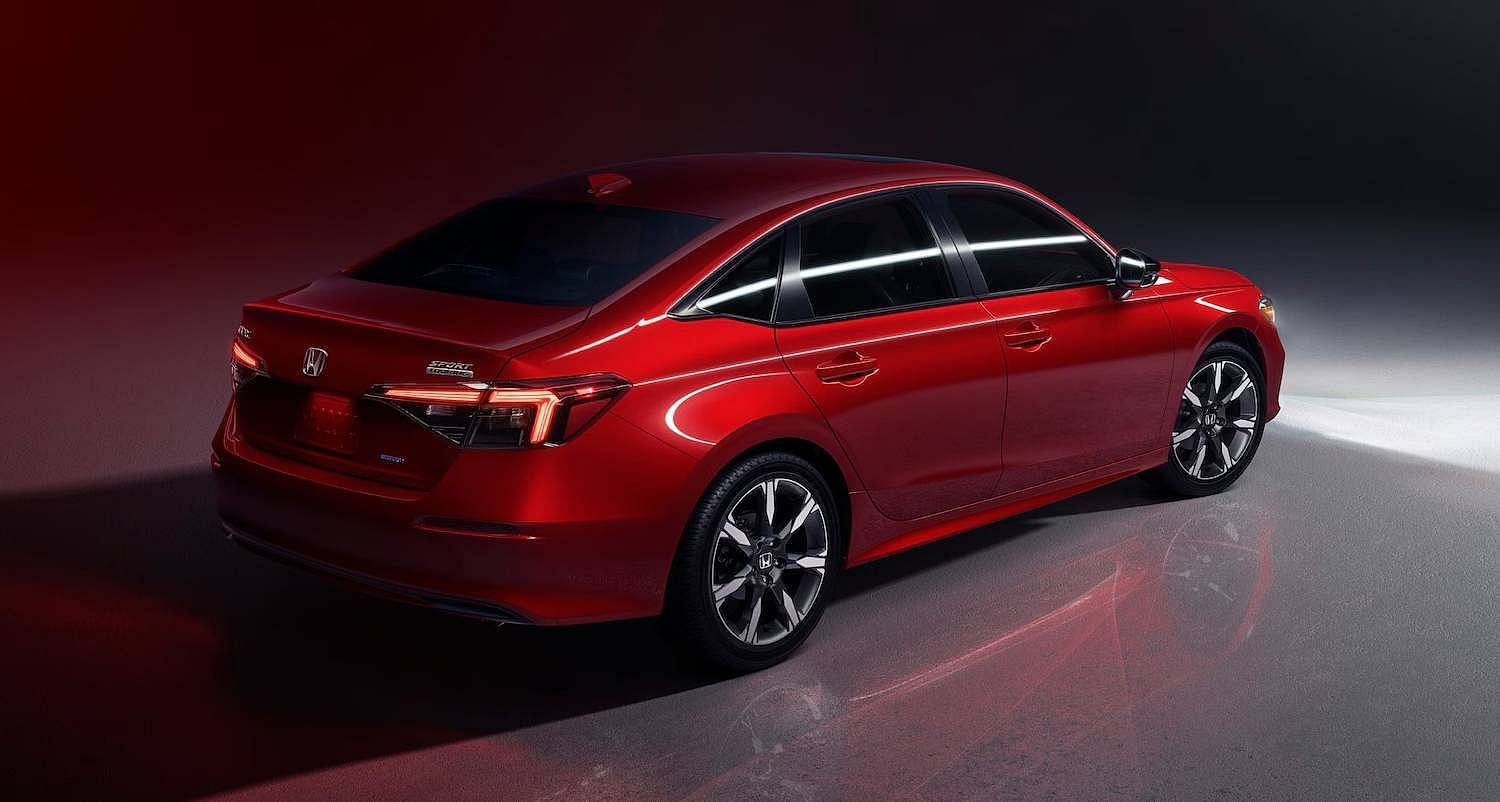 The 2025 Honda Civic Sedan Sport Touring Hybrid in Rallye Red at 7/8 rear passenger angle in studio environment