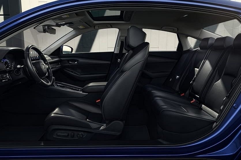 Interior view of a 2025 Honda Accord Hybrid showcasing black leather seats, a sleek dashboard, and ambient lighting, highlighting a spacious layout.