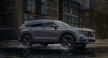 2026 CR-V Sport Touring driving on a city street through rainy conditions.