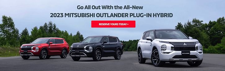 Red, black and white 2023 Mitsubishi Outlander Plug-in Hybrid parked on a street with trees in the background