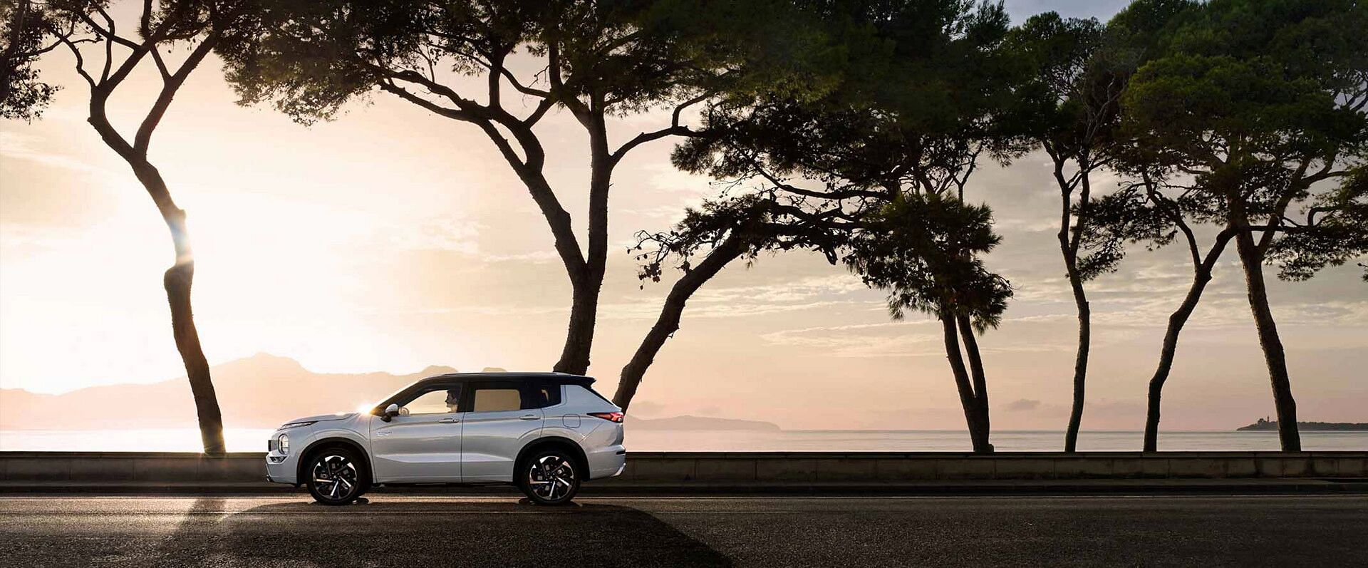 2023 Mitsubishi Outlander Plug-in Hybrid SUV driving on an empty road and on a scenic route