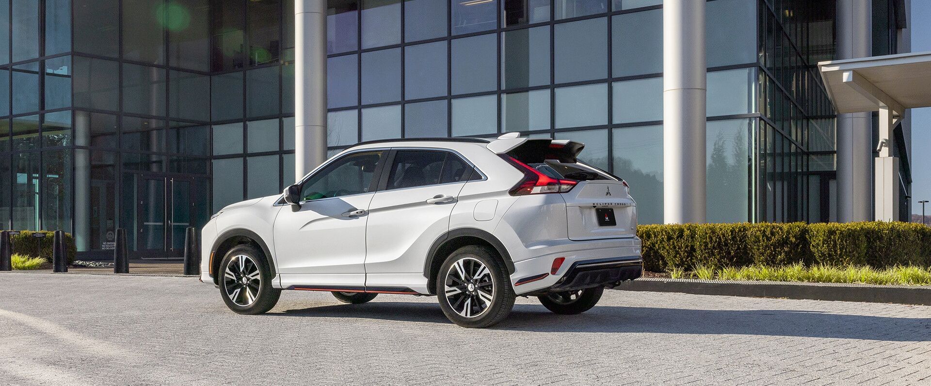 White 2023 Mitsubishi Eclipsce Cross standing on the street, against the backdrop of a glass building