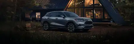 2027 Honda HR-V EX-L in Nordic Forest Pearl three quarter view parked in front of a cabin (Subcompact Crossover SUV).
