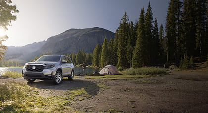 A silver Passport parked in the mountains by the lake.